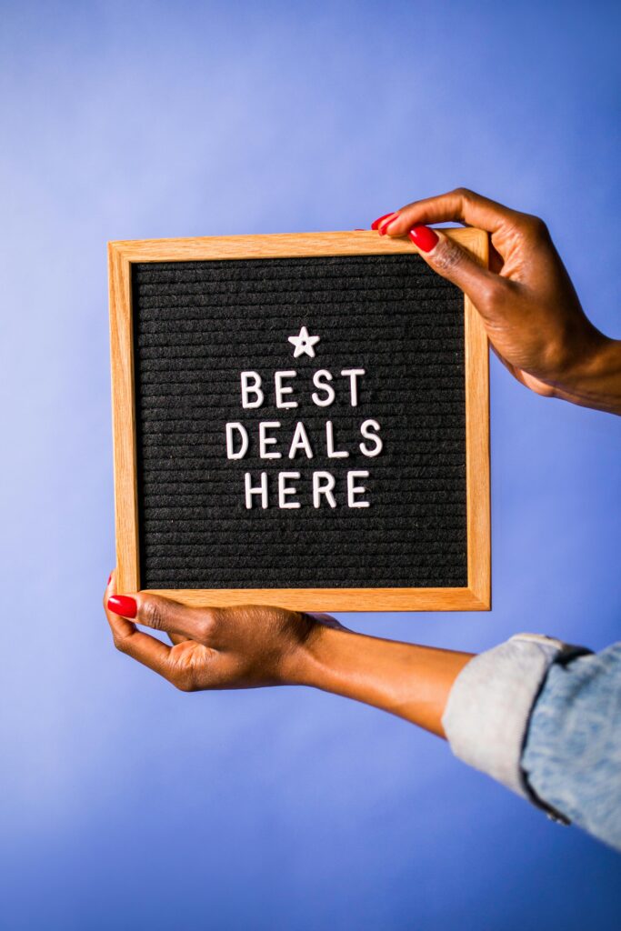 Photo of hands holding a letter board with 'best deals here' on a blue background.